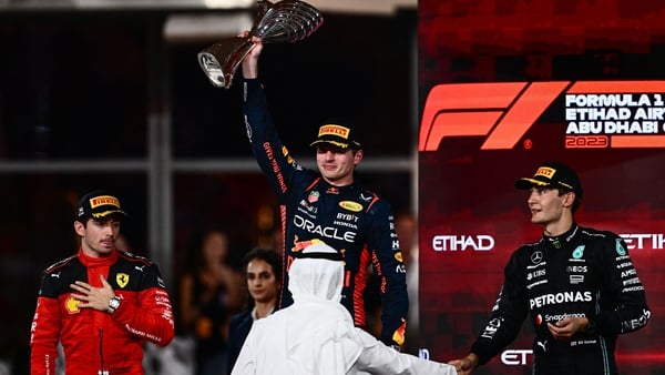 Max Verstappen (C) raises the winners' trophy as he stands on the podium with Ferrari's Charles Leclerc (L) and Mercedes' George Russell